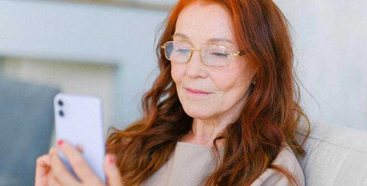 A person with red hair and glasses looking at a cellphone

Description automatically generated