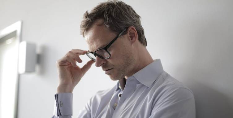 A man wearing glasses and touching his glasses