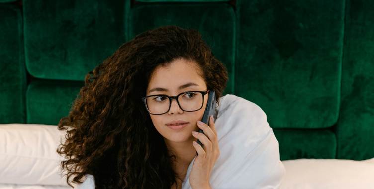 A person with long curly hair wearing glasses and a white blanket talking on a phone
AI-generated content may be incorrect.